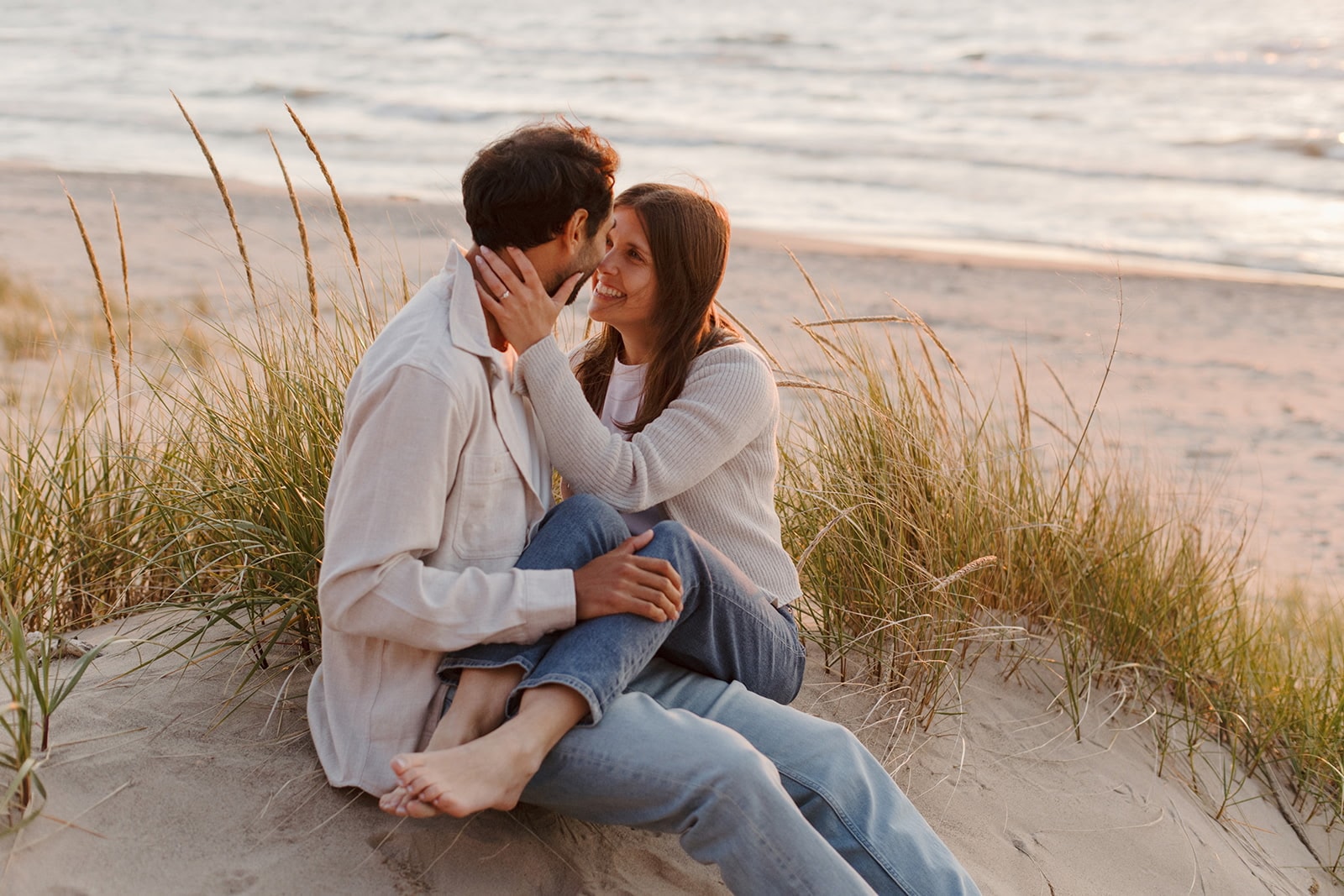Sarah and Stephane sitting together in the beach grass at sunset