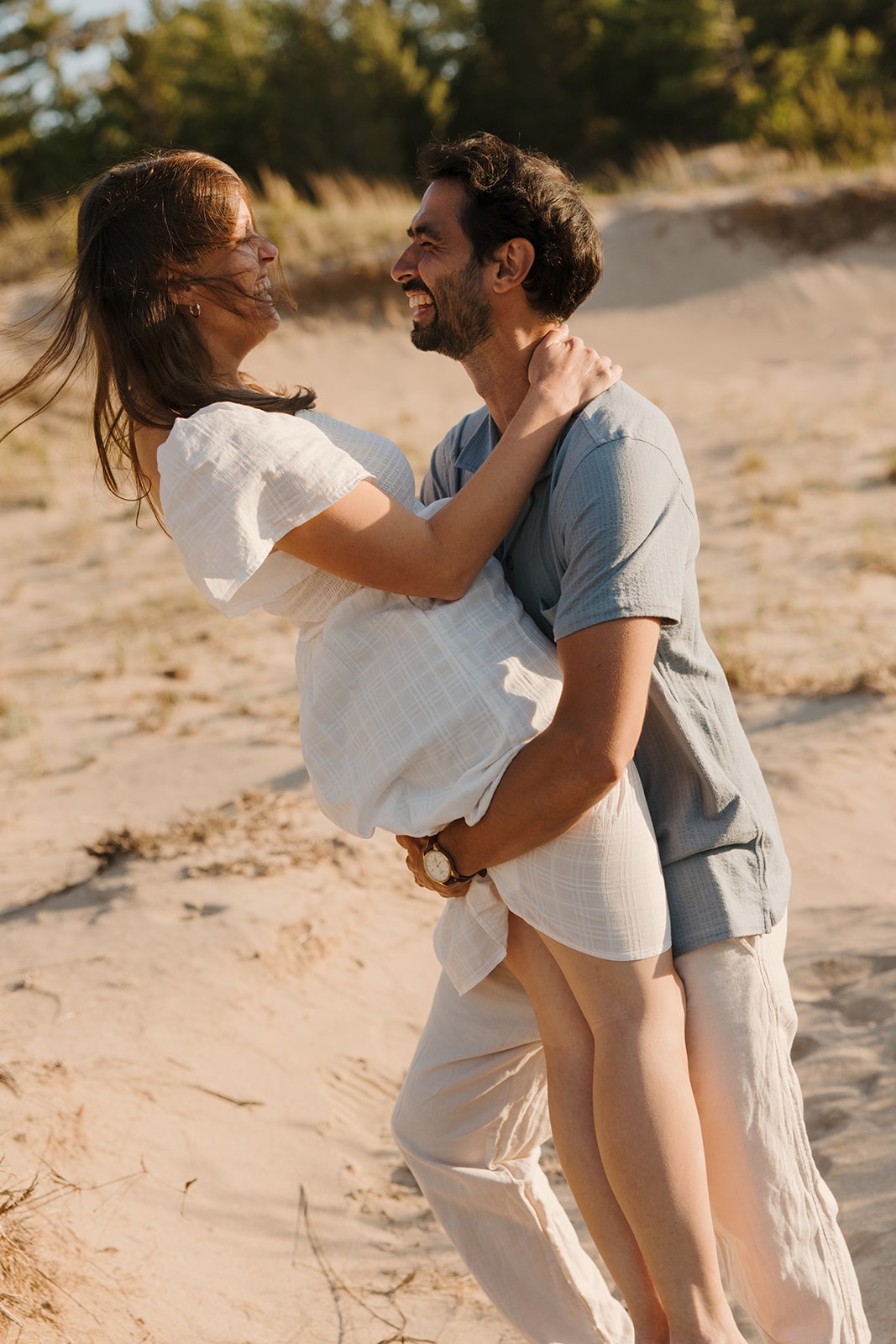 Stephane holding Sarah as they laugh together on the beach.
